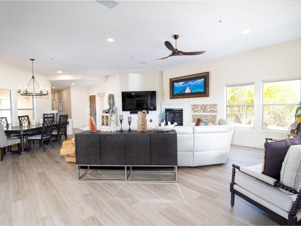 Bright neutral living room with beige sofas, warm wood flooring, and large windows