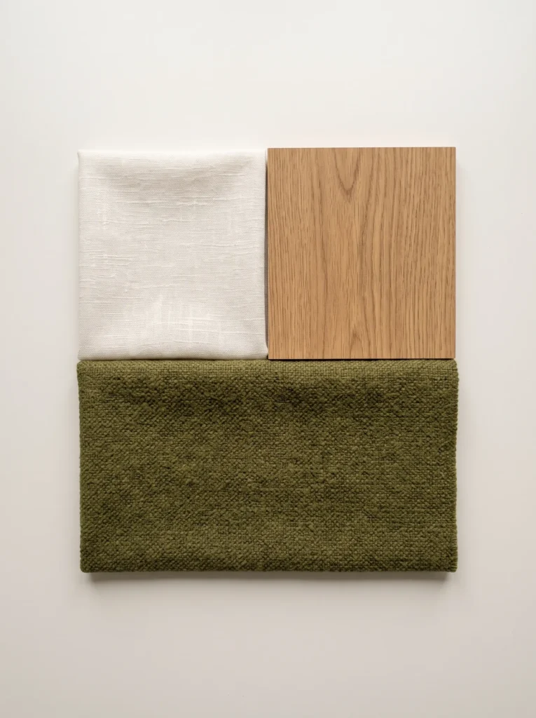 Warm-white fabric, medium-oak sample, and olive-green textile arranged on a plain surface.
